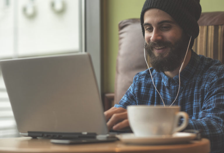 Young hipster man working on laptop in coffee shop