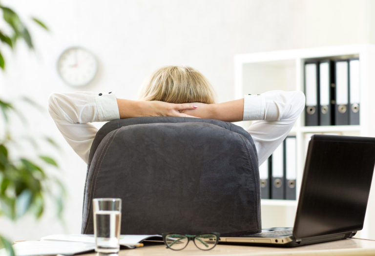 Businesswoman relaxing in office sitting back in chair with hands behind neck